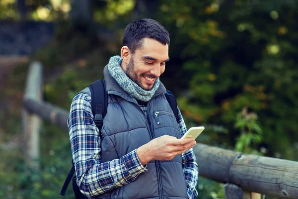 Gelukkig man met rugzak en smartphone outdoors — Stockfoto