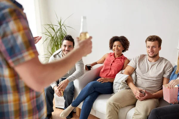 Amigos con palomitas de maíz y bebidas hablando en casa — Foto de Stock