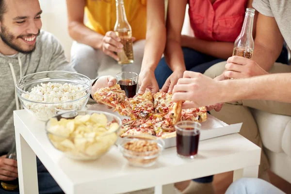 Gelukkige vrienden met dranken eten pizza thuis — Stockfoto