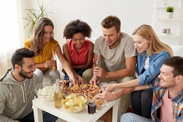 Happy přátelé s nápoji jíst pizzu doma — Stock fotografie