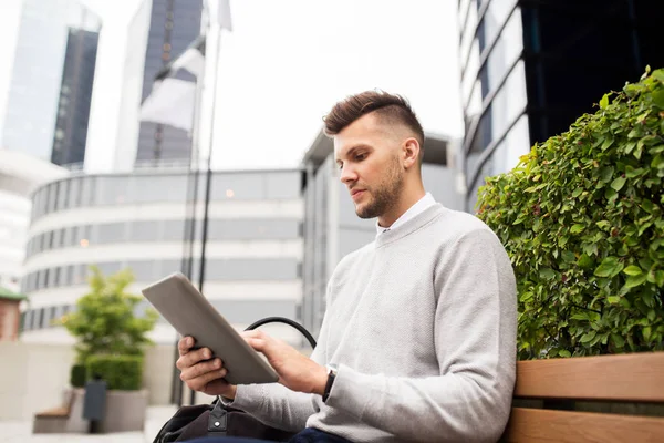Человек с планшетным компьютером, сидящий на городской уличной скамейке — стоковое фото