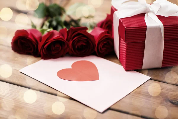 Primer plano de la caja de regalo, rosas rojas y tarjeta de felicitación — Foto de Stock