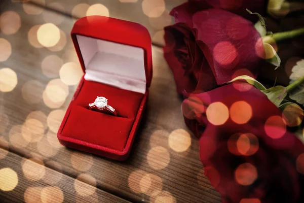 Närbild på diamant förlovningsring och röda rosor — Stockfoto