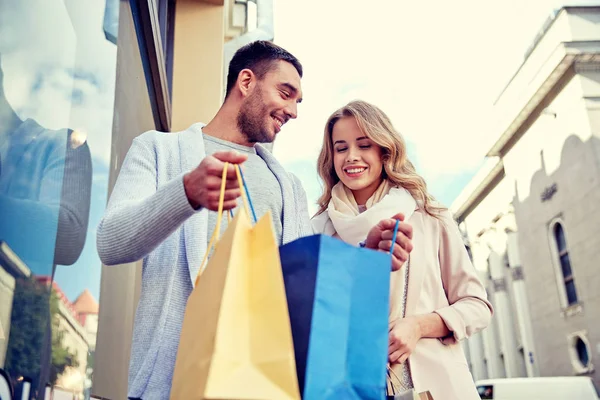 Casal feliz com sacos de compras na vitrine da loja — Fotografia de Stock