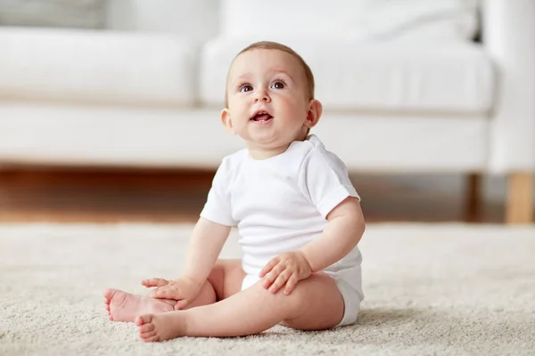 Glücklicher kleiner Junge oder Mädchen, die zu Hause auf dem Boden sitzen — Stockfoto