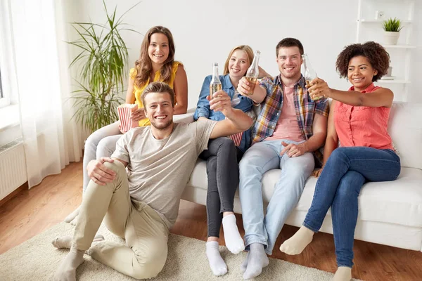 Amigos felizes com pipocas e cerveja em casa — Fotografia de Stock