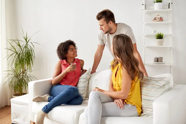 Groep gelukkige vrienden met dranken thuis praten — Stockfoto