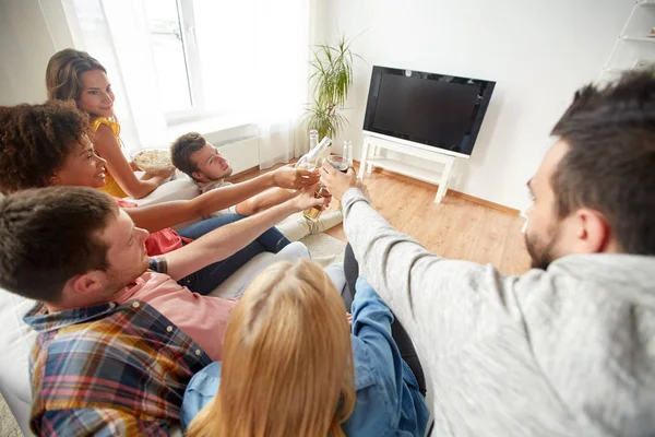 Amigos clinking cerveja e assistindo tv em casa — Fotografia de Stock
