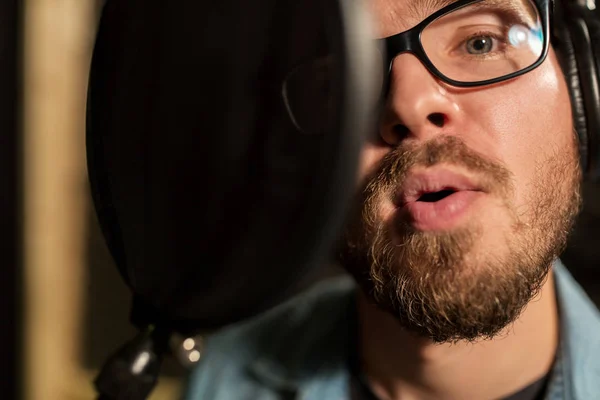 Man with headphones singing at recording studio — Stock Photo, Image