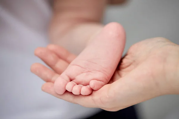 Primo piano del piede del neonato nella mano della madre — Foto Stock