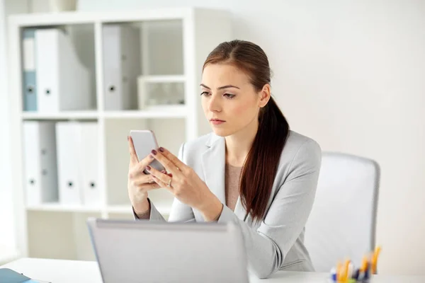 Empresária com smartphone no escritório — Fotografia de Stock