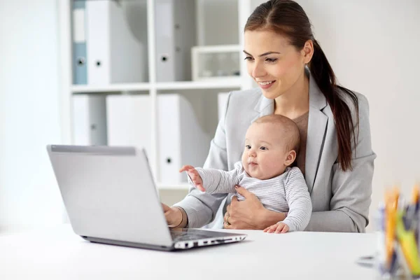 Szczęśliwa kobieta interesu z baby i laptopa w biurze — Zdjęcie stockowe