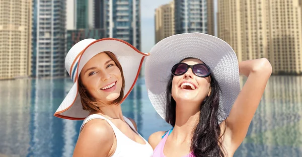 Gelukkig jonge vrouwen in hoeden op zomer-strand — Stockfoto