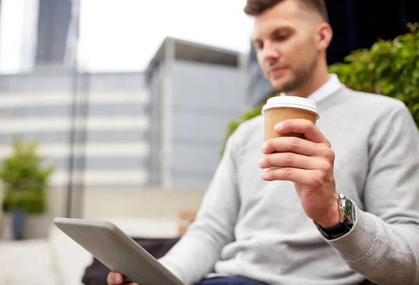 Человек с планшетным компьютером и чашкой кофе на городской улице — стоковое фото