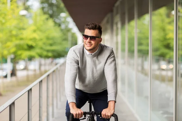 Młody człowiek w odcieniach jazda roweru na miasto ulica — Zdjęcie stockowe