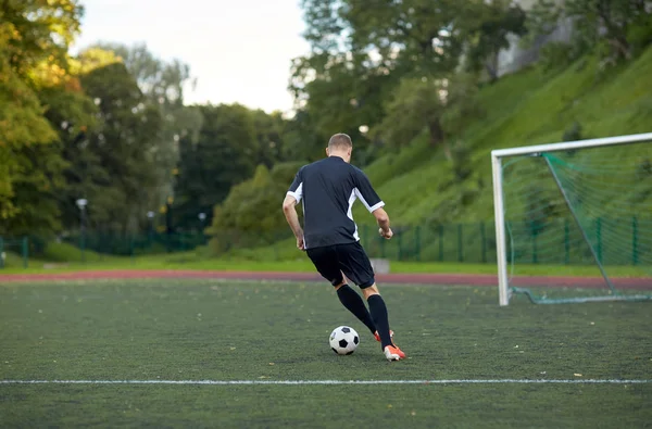 Fotbalový hráč hraje s míčem na fotbalové hřiště — Stock fotografie