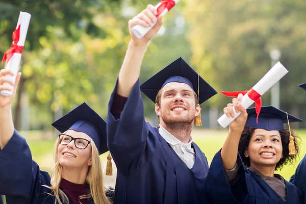 Estudiantes felices en morteros con diplomas — Foto de Stock