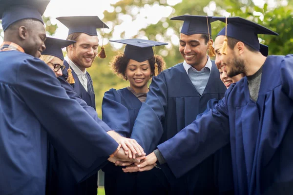 Estudiantes felices en morteros con las manos en la parte superior — Foto de Stock