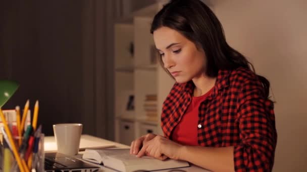 Opiskelija tyttö tai nainen lukee kirjaa yöllä kotona — kuvapankkivideo