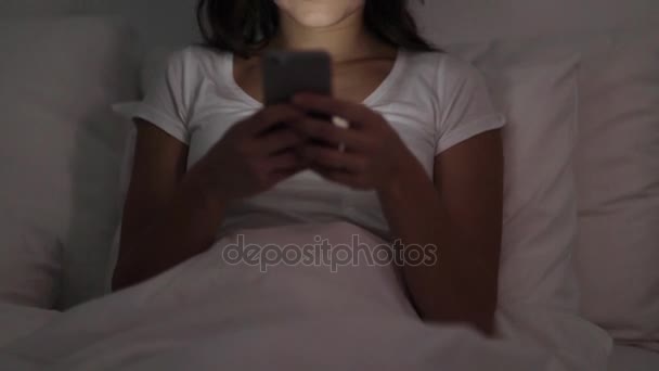 Feliz joven con teléfono inteligente en la cama por la noche — Vídeos de Stock