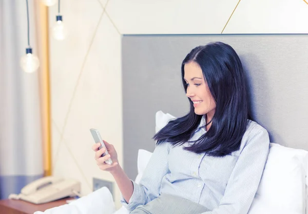 Happy businesswoman with smartphone in hotel room — Stock Photo, Image