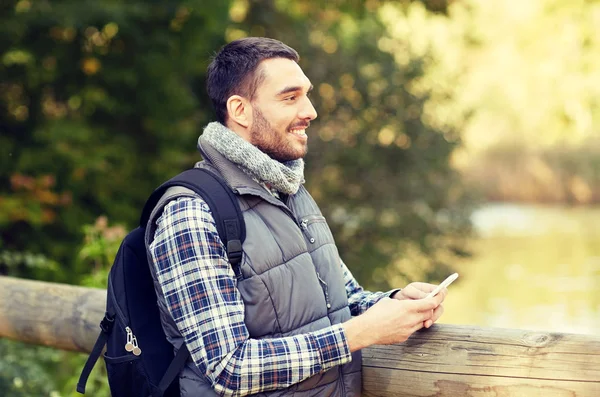 Glücklicher Mann mit Rucksack und Smartphone im Freien — Stockfoto