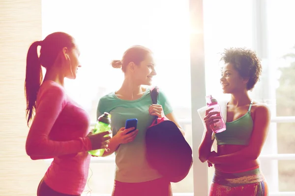 Glada kvinnor med flaskor vatten i gym — Stockfoto