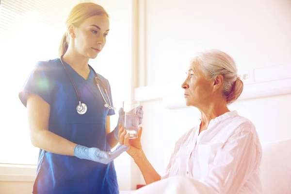Nurse giving medicine to senior woman at hospital — Stock Photo, Image