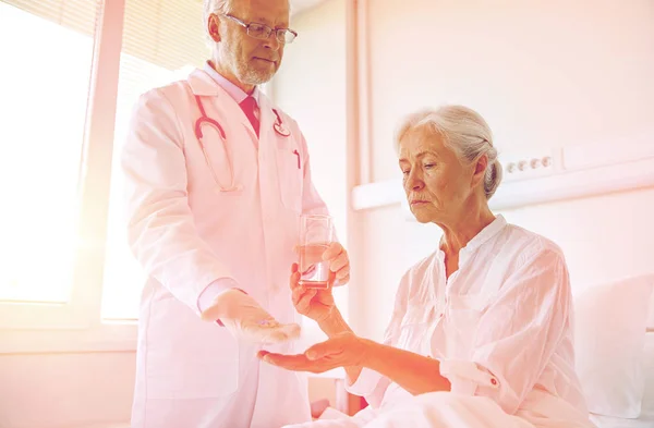 Doctor giving medicine to senior woman at hospital — Stock Photo, Image