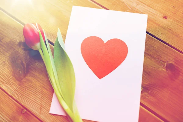 Perto de flores e cartão de saudação com coração — Fotografia de Stock