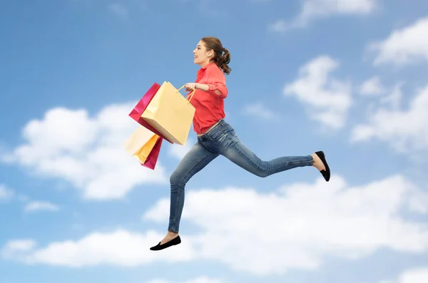Усміхнена молода жінка з сумками стрибає — стокове фото
