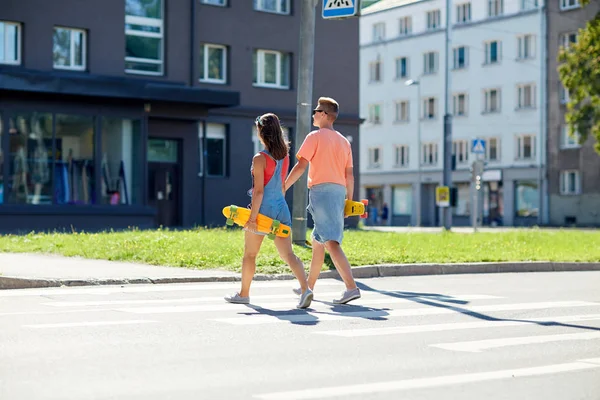 Pareja adolescente con patinetas en la ciudad crosswalk —  Fotos de Stock