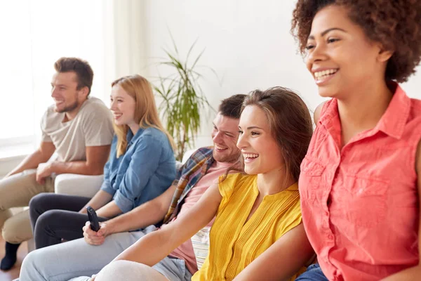 Amici felici con telecomando guardando la tv a casa — Foto Stock