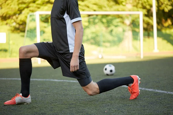 Jogador de futebol esticando a perna no campo de futebol — Fotografia de Stock