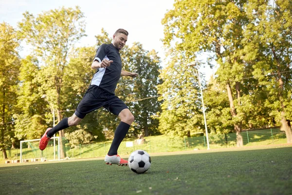 Jogador de futebol jogando com bola no campo de futebol — Fotografia de Stock