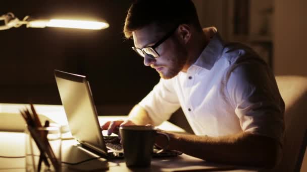 Mann mit Laptop und Papieren arbeitet nachts im Büro — Stockvideo