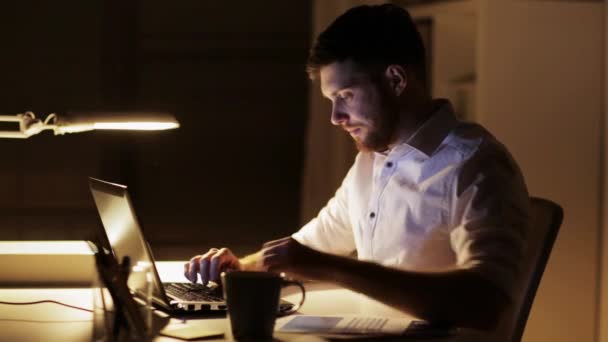 Man met laptop en smartphone bij nacht kantoor — Stockvideo