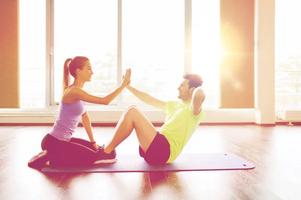 Mulher com personal trainer fazendo sit ups no ginásio — Fotografia de Stock