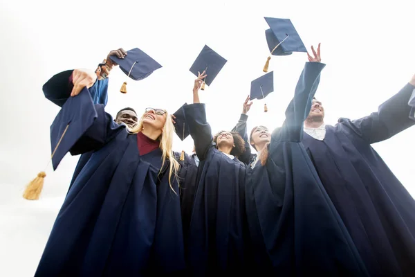 Estudantes felizes jogando placas de argamassa para cima — Fotografia de Stock