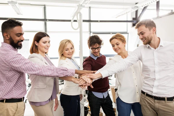 Happy business-team med händerna på topp på office — Stockfoto