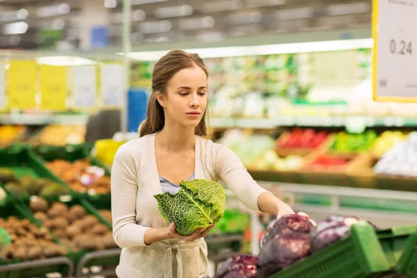 Счастливая женщина покупает колбасу в продуктовом магазине — стоковое фото