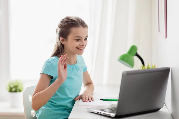 Gelukkig meisje met laptop zwaaien hand thuis — Stockfoto