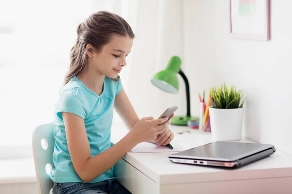 Chica con el ordenador portátil y el teléfono inteligente mensajes de texto en casa —  Fotos de Stock