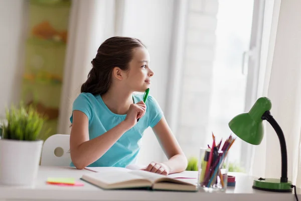 Menina feliz com livro escrevendo para notebook em casa — Fotografia de Stock