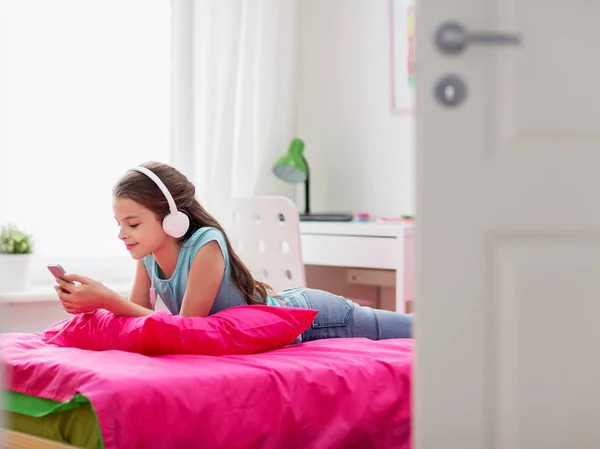 Mädchen mit Kopfhörer und Smartphone zu Hause — Stockfoto