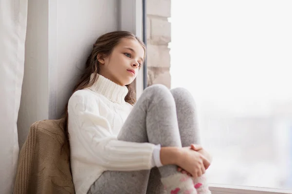 Triste chica sentado en alféizar en casa ventana en invierno — Foto de Stock