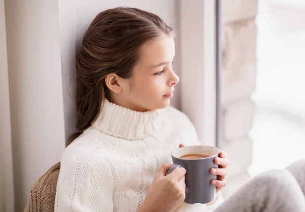 Flicka med cacao mugg sitter hemma fönster — Stockfoto