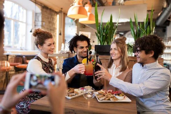 Счастливые друзья звонят напитки в баре или кафе — стоковое фото