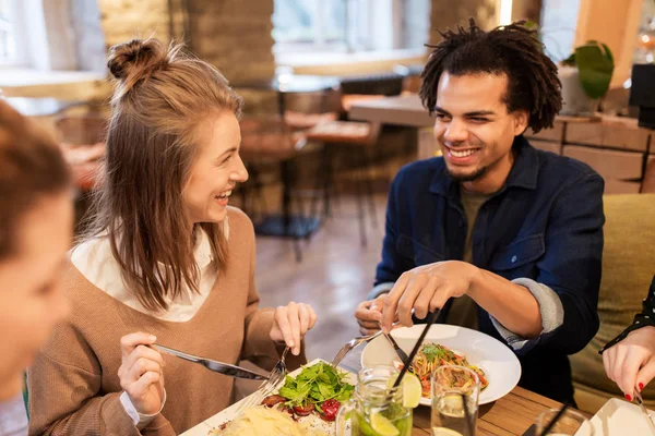Amigos felizes comendo e bebendo no restaurante — Fotografia de Stock