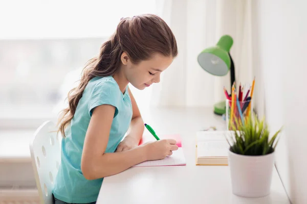 Happy girl with book writing to notebook at home Stock Picture